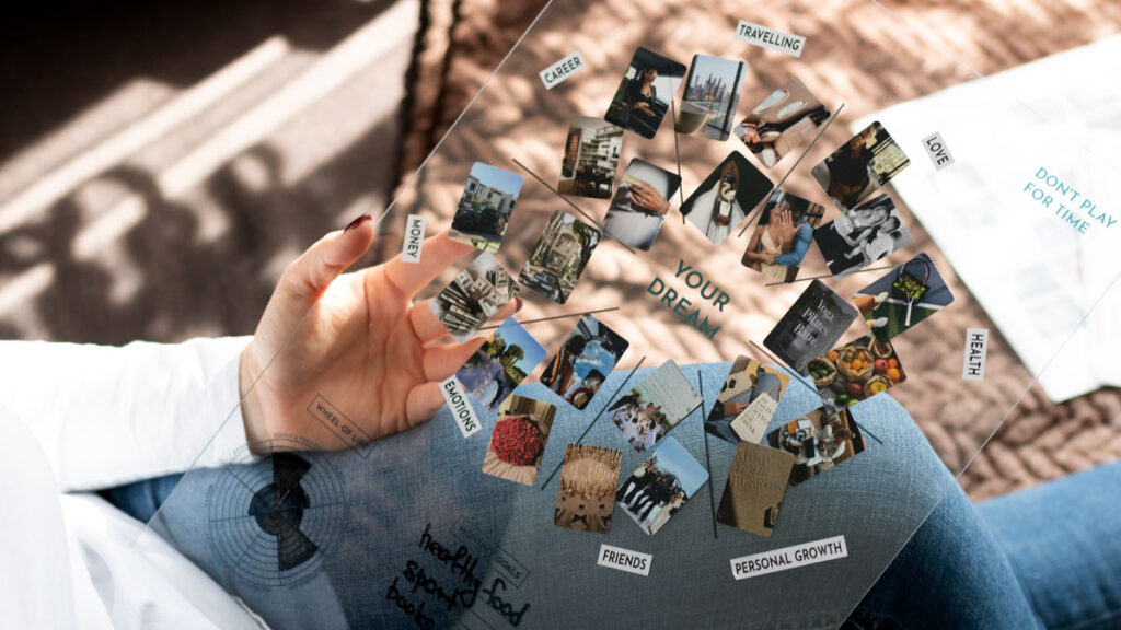 A creative visualization of a Dream-Map in use, showcasing a woman's hand arranging transparent cards with images and words like 'Traveling', 'Health', and 'Personal Growth' over a diary, symbolizing the planning and realization of dreams and aspirations.